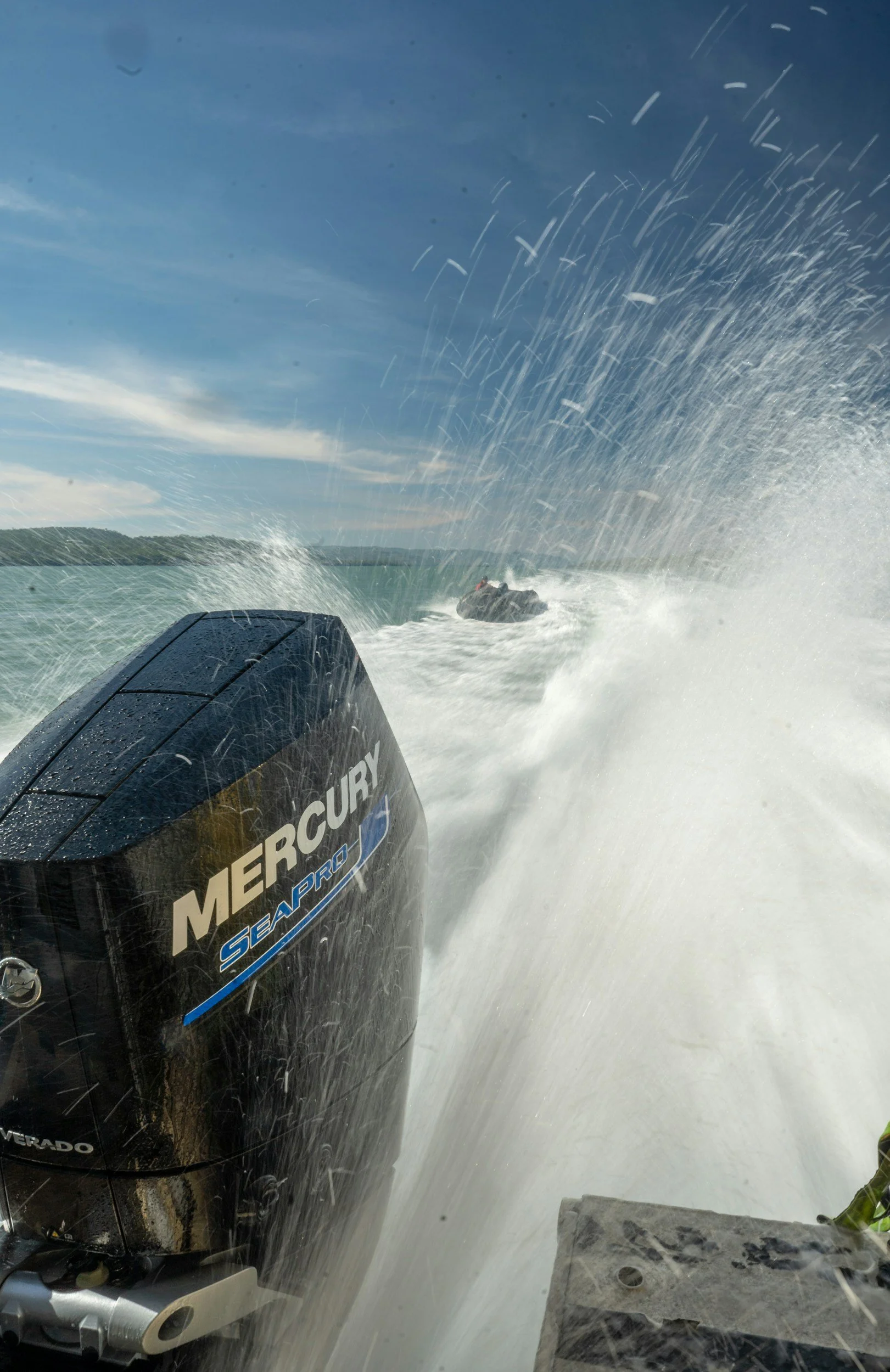Mercury SeaPro outboard motor powering a boat while people ride an inflatable tube on the water.