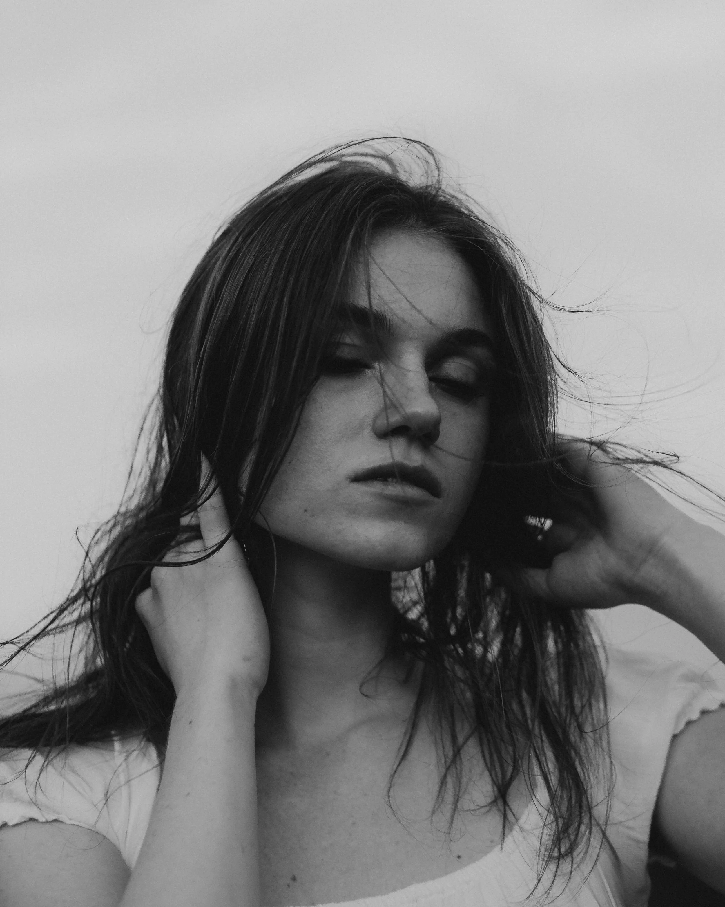 Black and white portrait of a woman with long hair, closed eyes, and a relaxed pose.