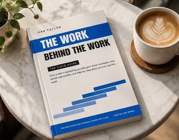 The Work Behind the Work: The Field Guide by Dan Taylor on a cafe table next to a latte
