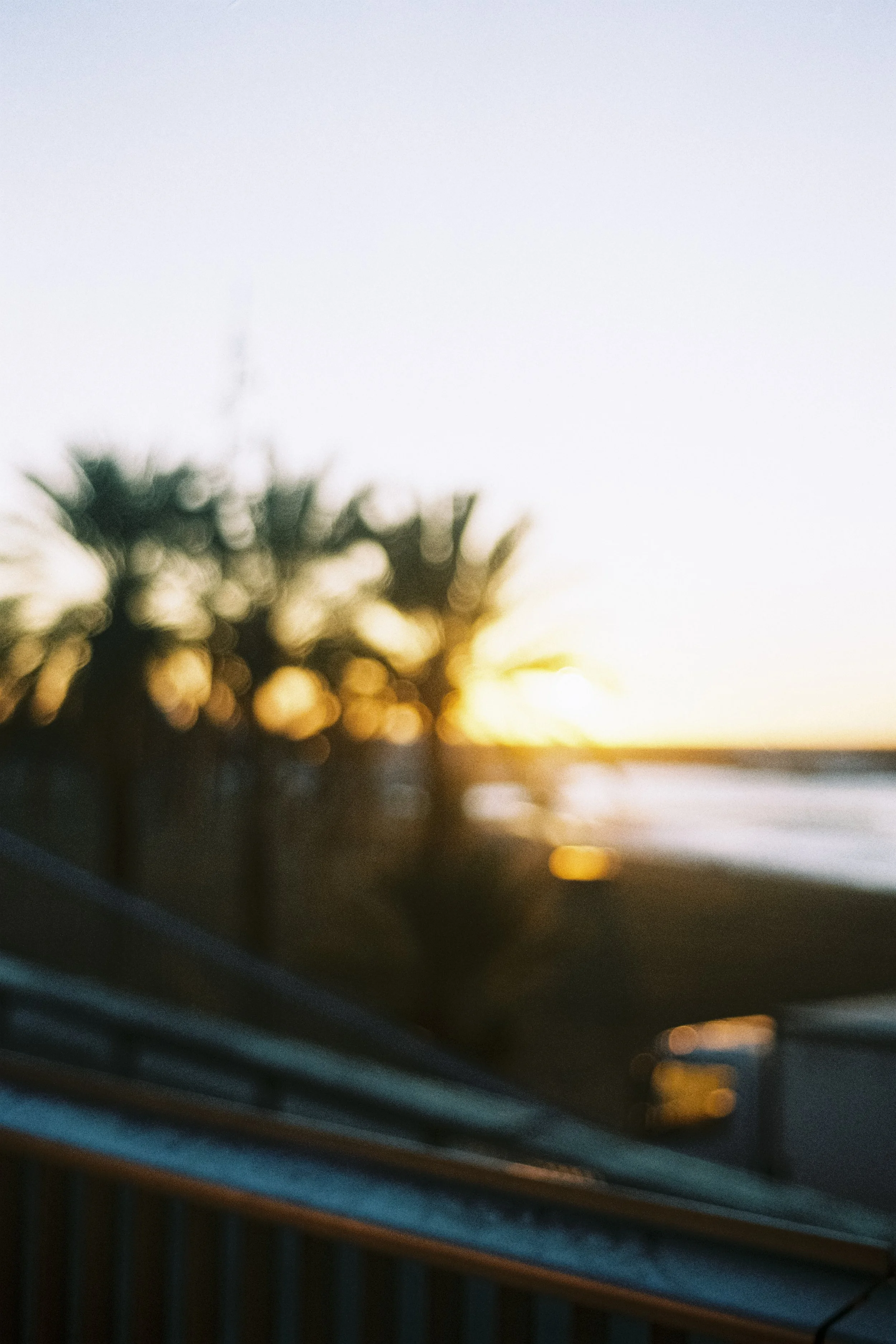 Cliché flou d'une plage au coucher du soleil avec des palmiers en silhouette. Barcelone plage de la Barcelonetta, photographie argentique artistique, design.