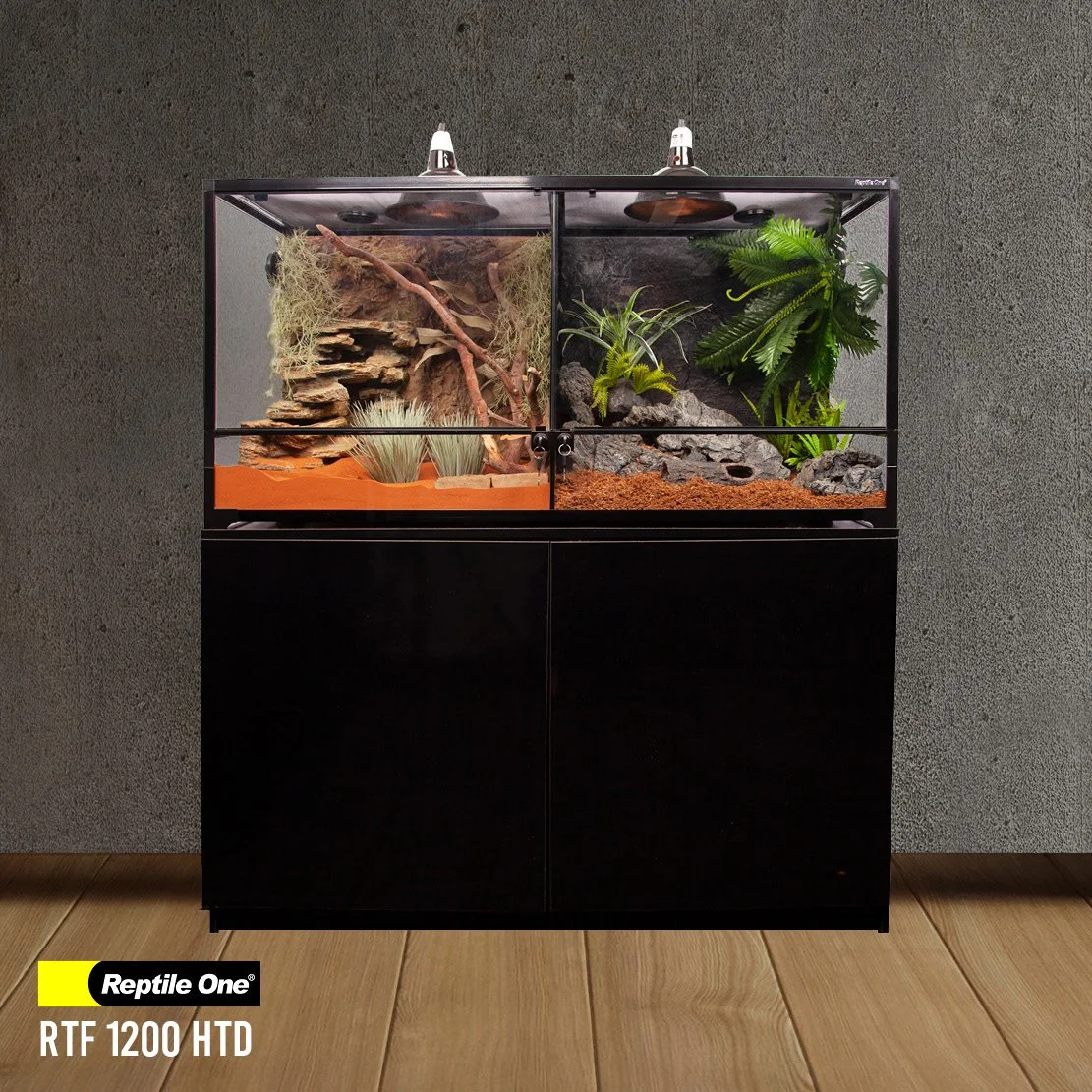 A glass reptile enclosure with plants, rocks, and wood inside, placed on a black cabinet against a gray wall.