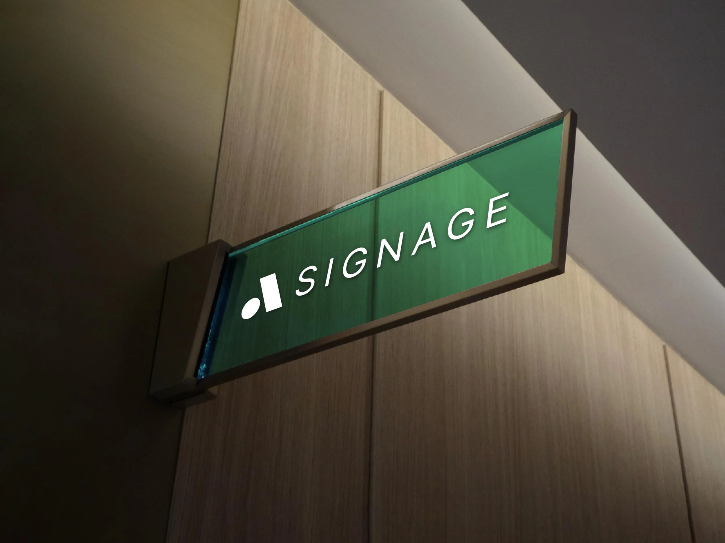 Green lit sign with the word 'SIGNAGE' in white letters and an abstract symbol to the left, mounted on a wall in an indoor setting.