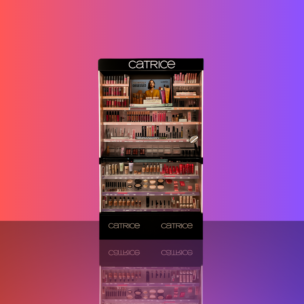 Display shelf of Catrice makeup products against a gradient pink and purple background, with reflections on a glossy surface.