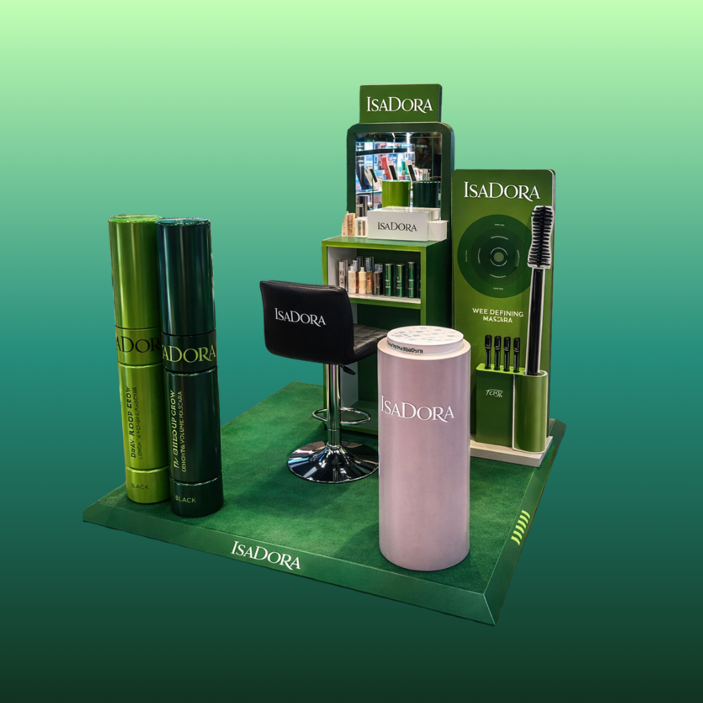 Display stand for Isadora hair products with green and black packaging, a black chair with the Isadora logo, a mirror, and promotional materials on a green platform.