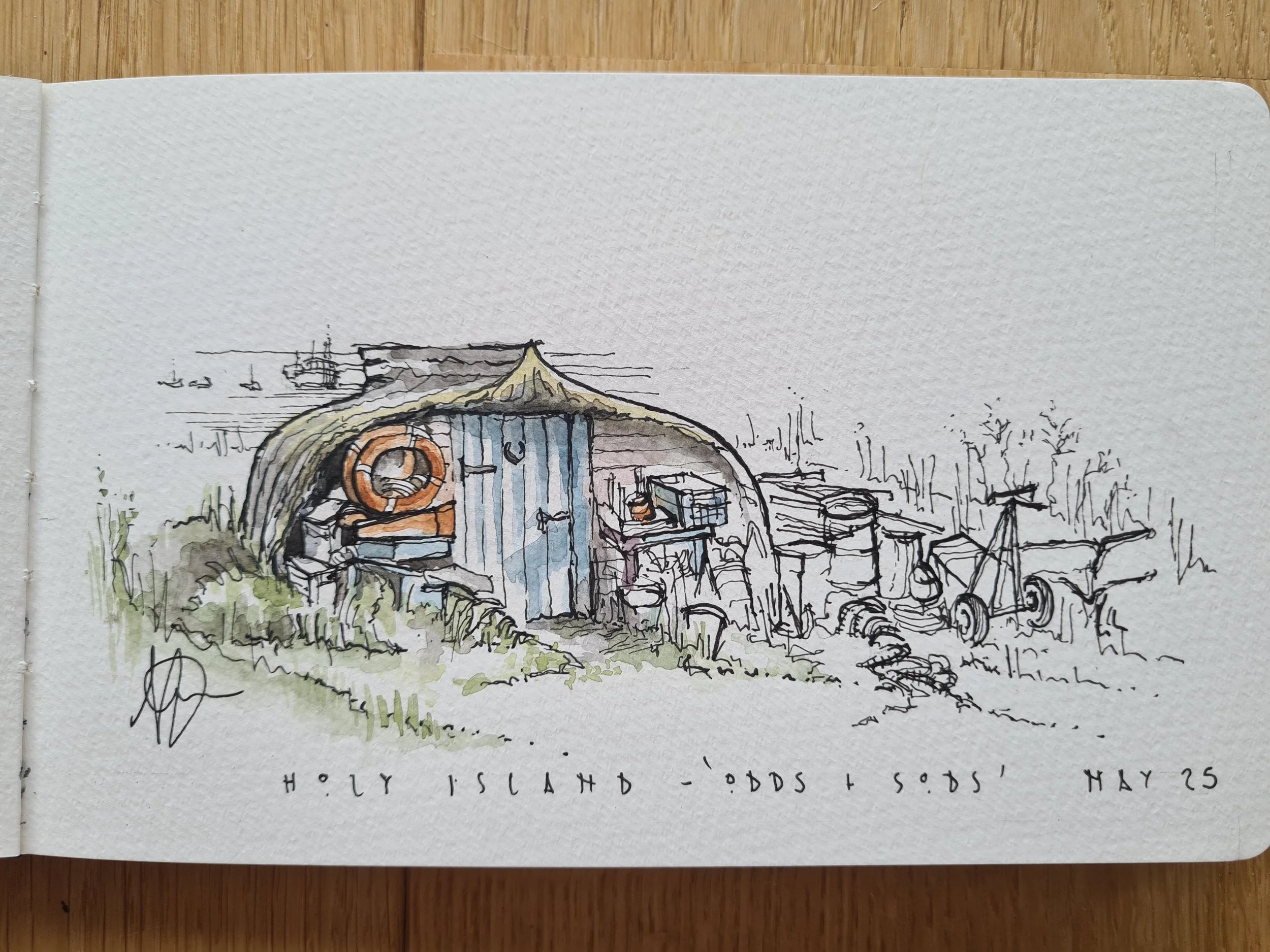 A hand-drawn sketch of a small shed with a curved roof, painted in blue and orange, situated on Holy Island. The background shows a landscape with scattered trees and some distant boats or ships. The sketch includes some barrels and construction tool