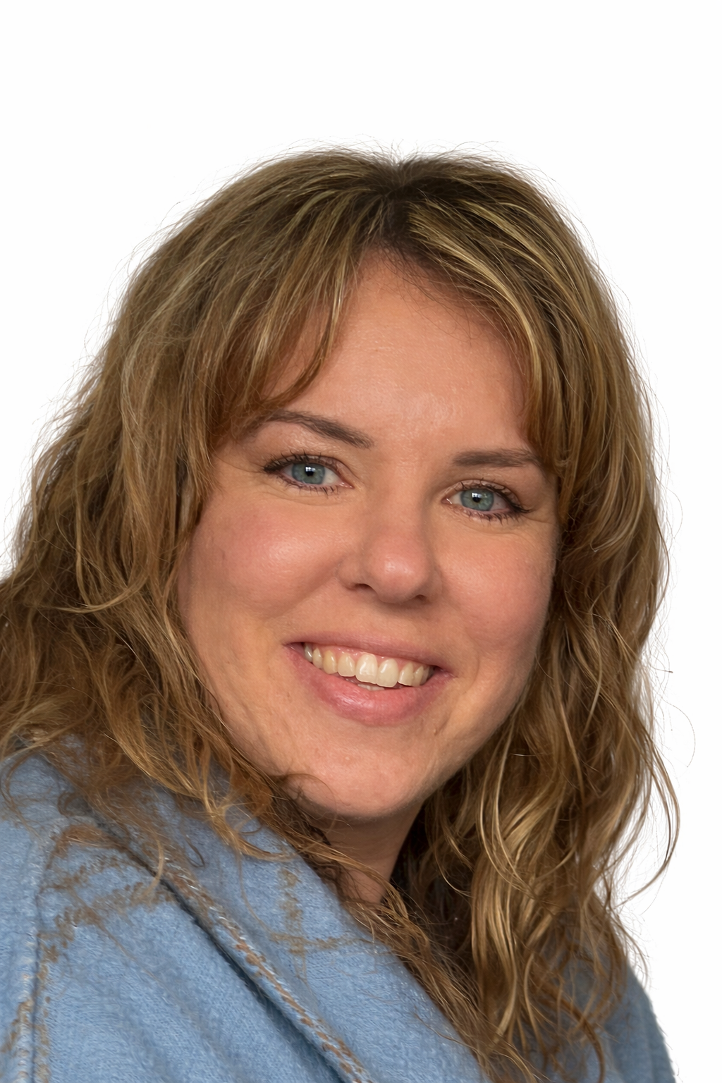 A woman with wavy blonde hair, blue eyes, and a big smile, wearing a denim jacket.