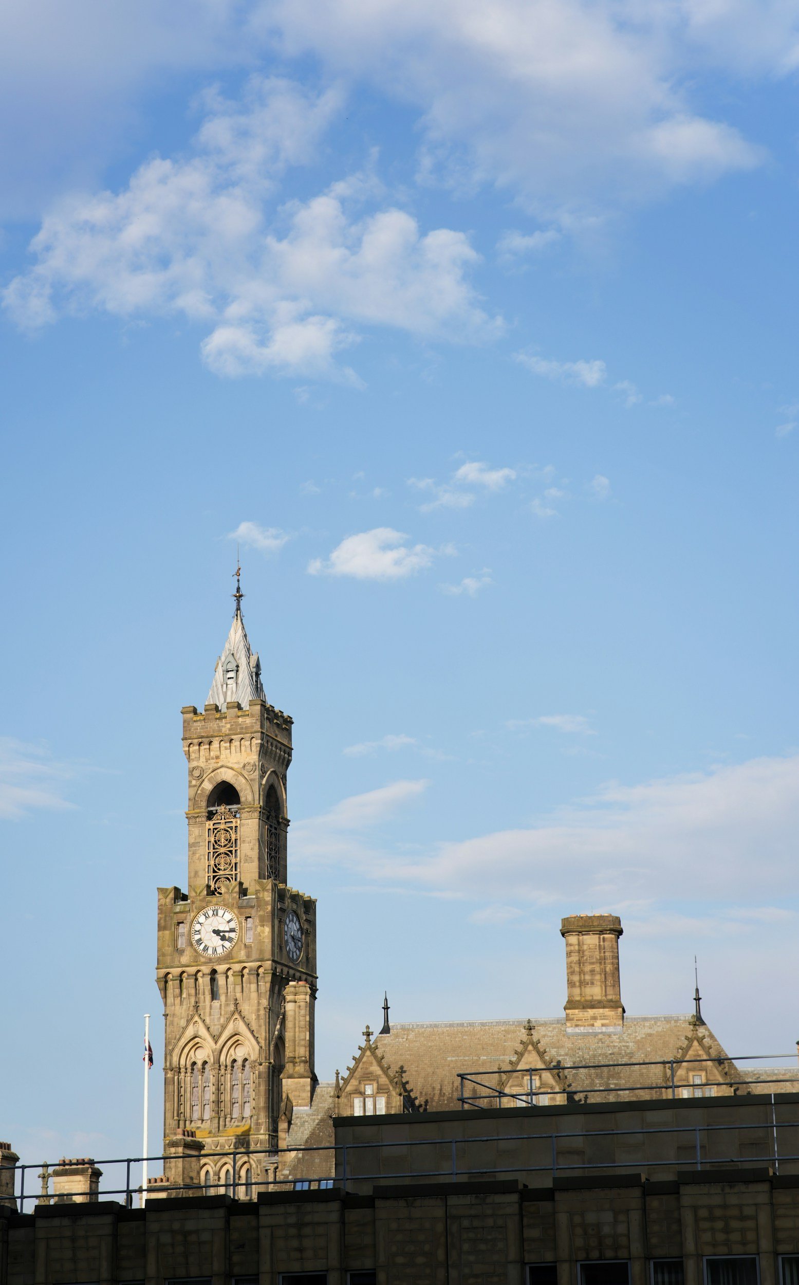 A historic clock tower on a stone building with a blue sky and scattered clouds in the background.