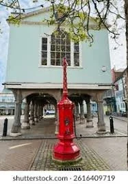 A red fire hydrant in front of a light blue building with columns and a large arched window