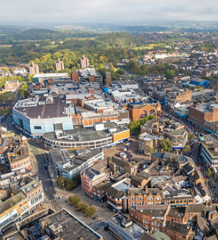 Aerial view of an urban area with a mix of modern and historic buildings, roads, and green spaces.