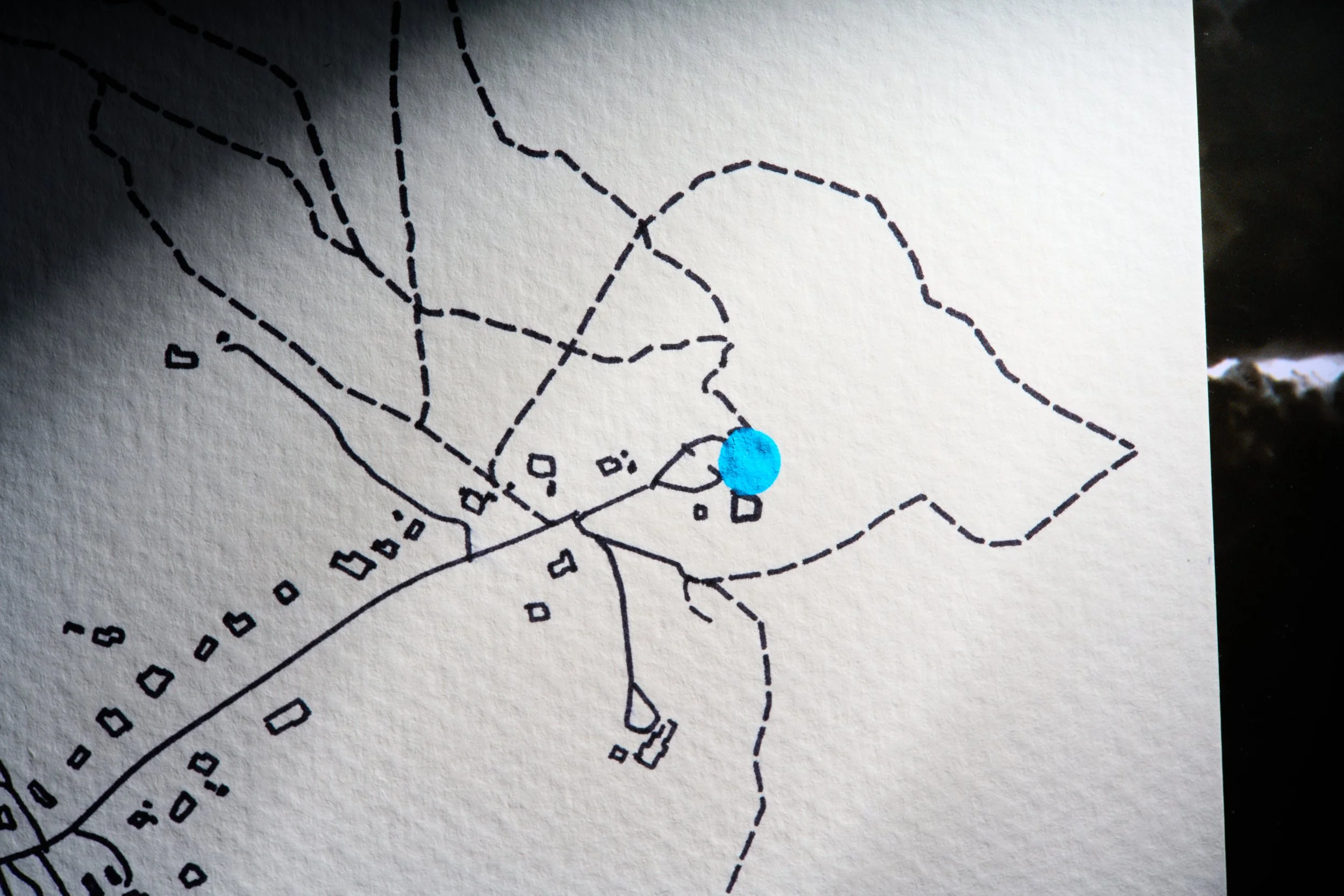 A mountain landscape with snow-capped peaks, rolling green and brown hills, and a modern building in the foreground.