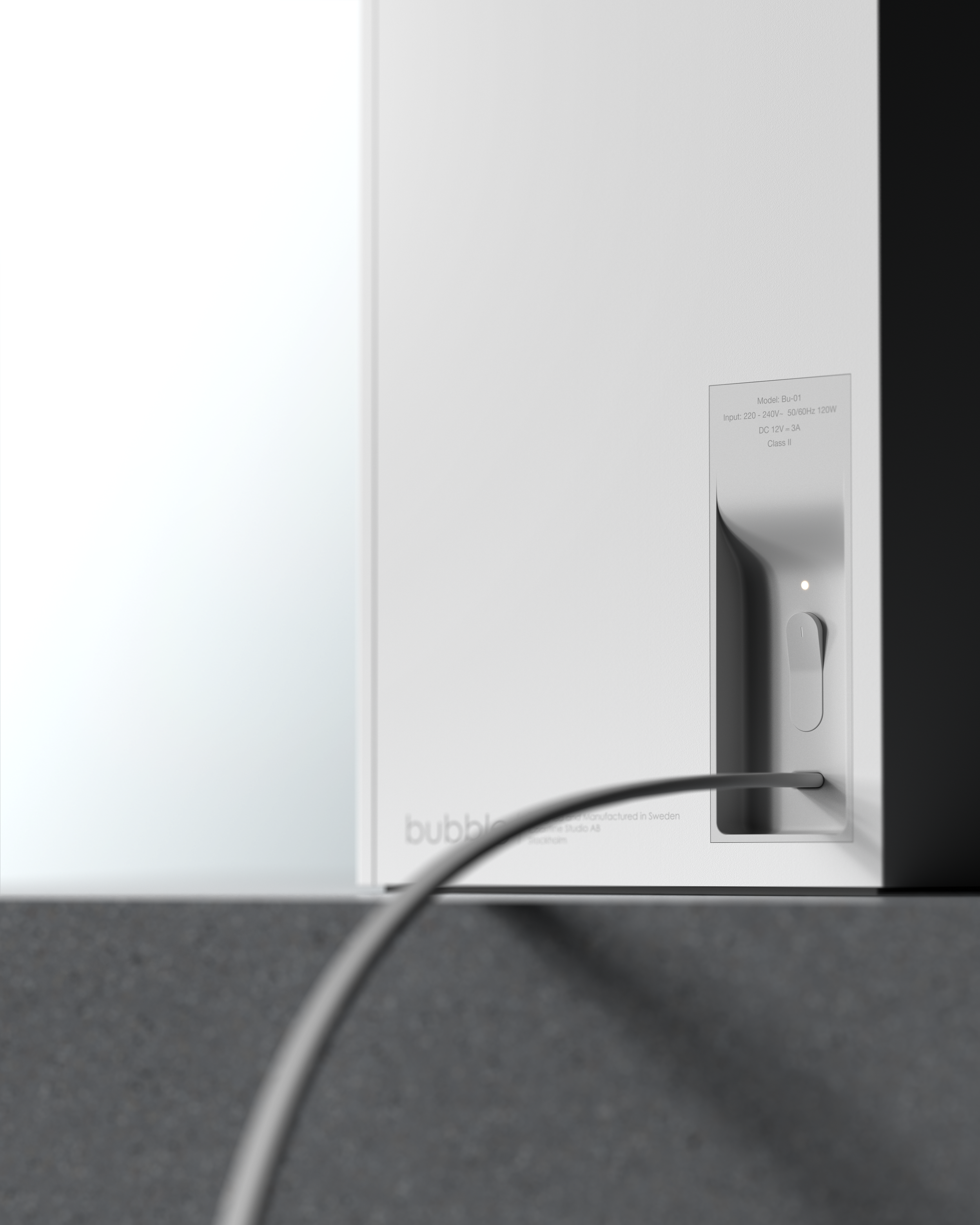 A white Bubble coffee machine on a gray countertop, with a power cord plugged into an outlet.