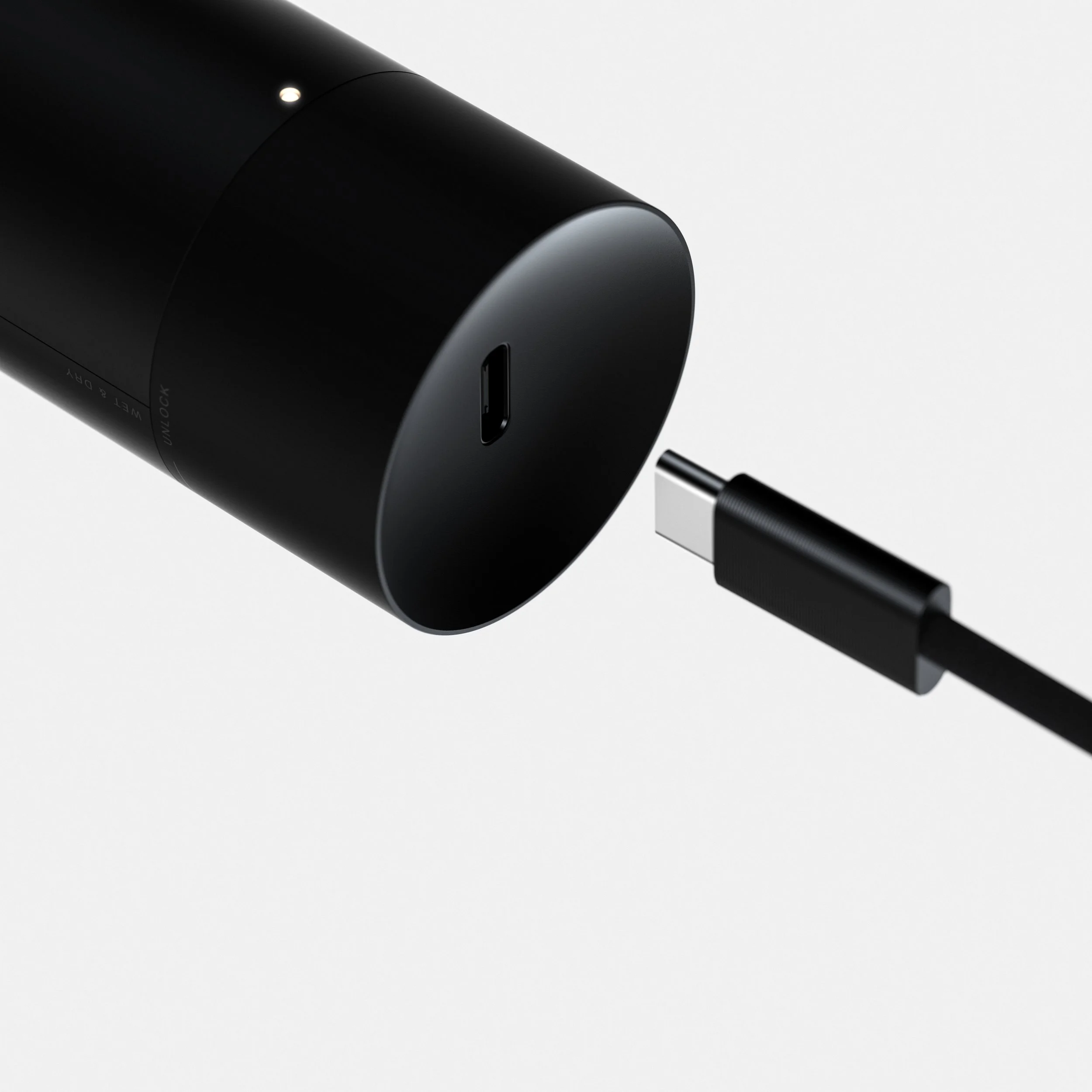 A black cylindrical electronic device with a USB-C port on one end, connected to a black cable with a USB-C connector, set against a plain white background.