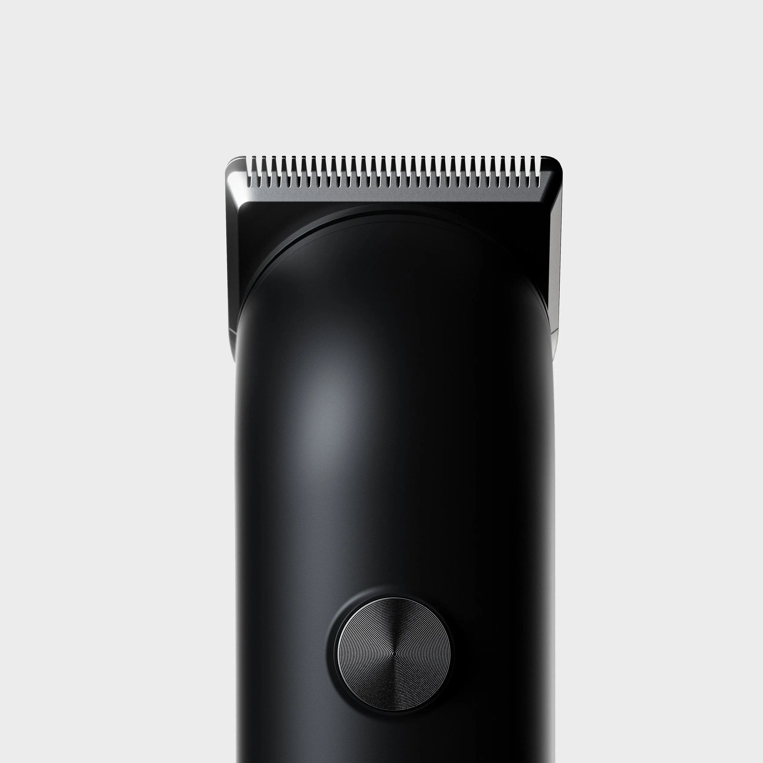 Close-up of a black electric hair clipper with a textured control dial on a plain light background.