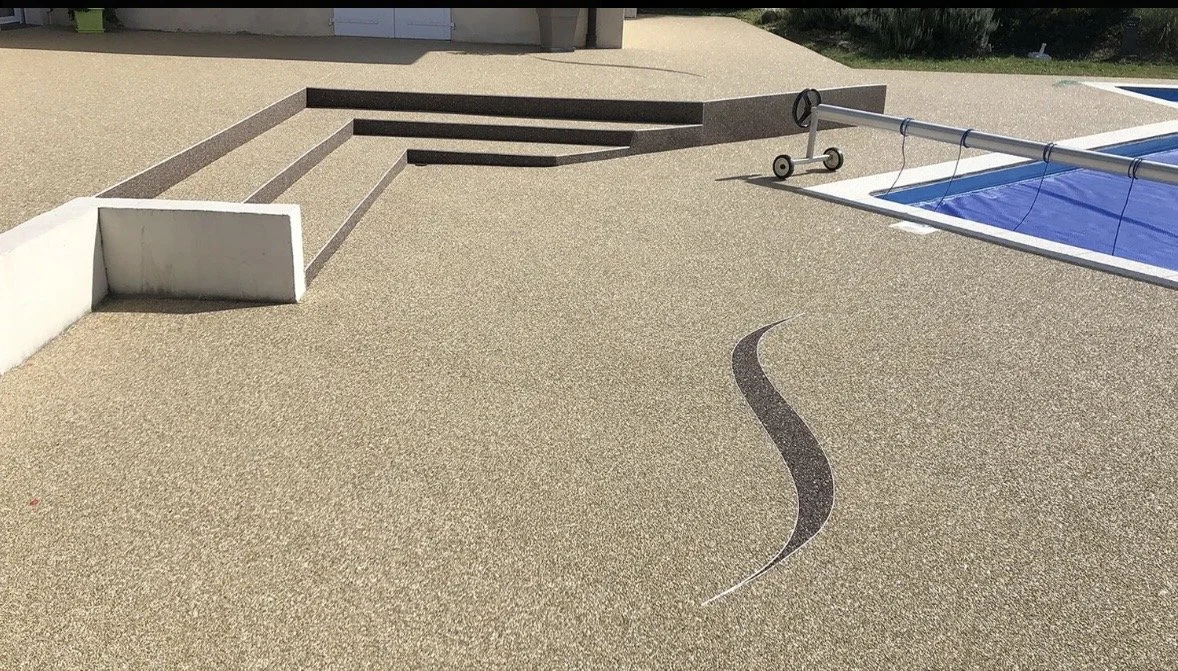 Surface en béton avec un dessin en zigzag, une piscine couverte et des escaliers.