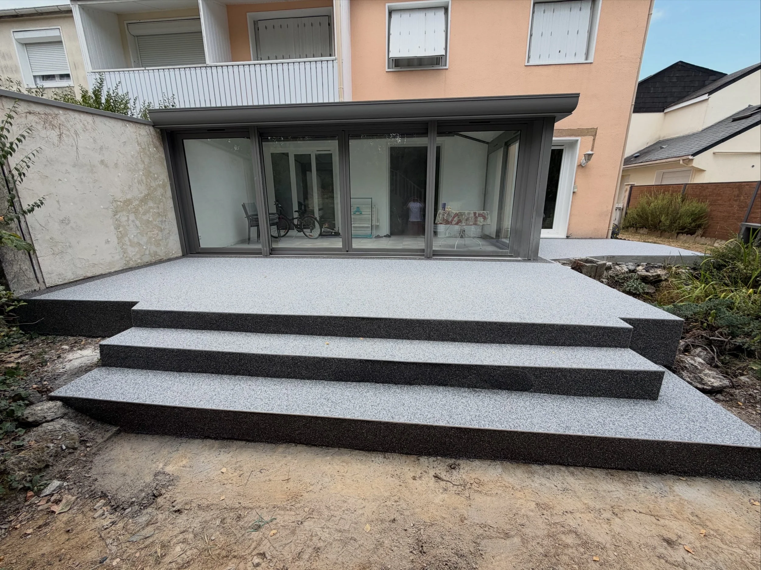 Terrasse et escalier extérieur en moquette de pierre gris clair avec bordures foncées