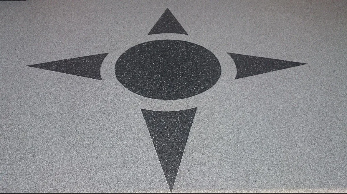 Symbole géométrique avec un cercle central entouré de quatre triangles pointant dans différentes directions sur une surface grise.