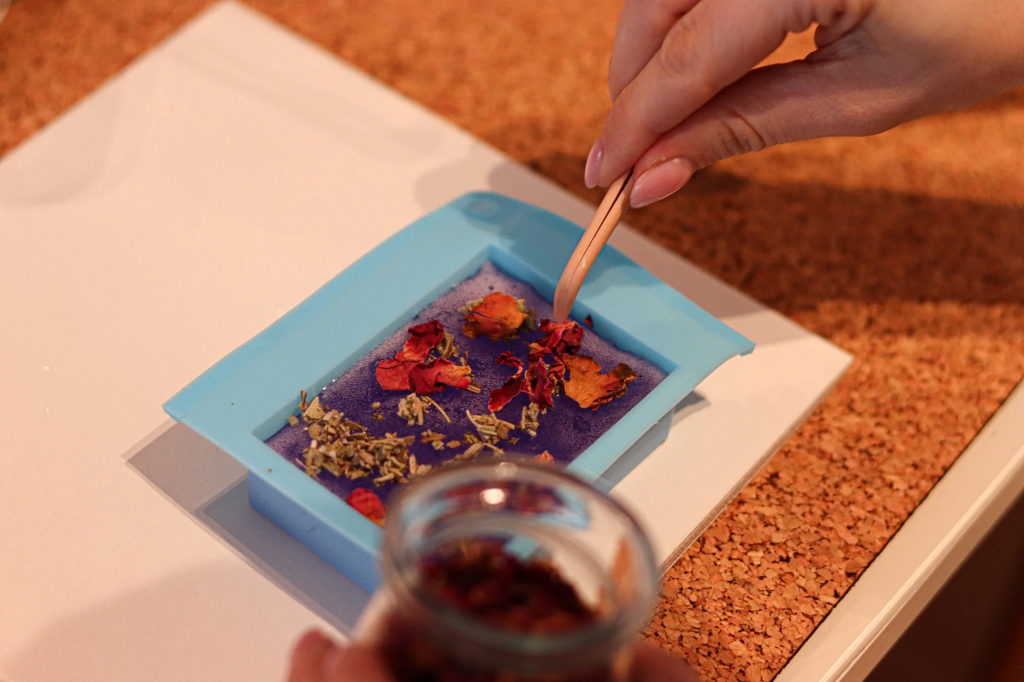 Eine handgemachte Seife wurde in die Silikonform gegossen und wird mit einer Pinzette und getrockneten Blumen verziert.