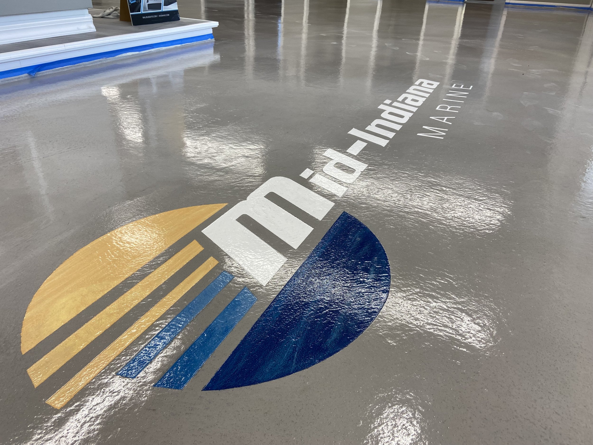 Marina floor with painted logo and text reading "INDIAN RIVER MARINE" in white, yellow, and blue on a polished concrete surface.