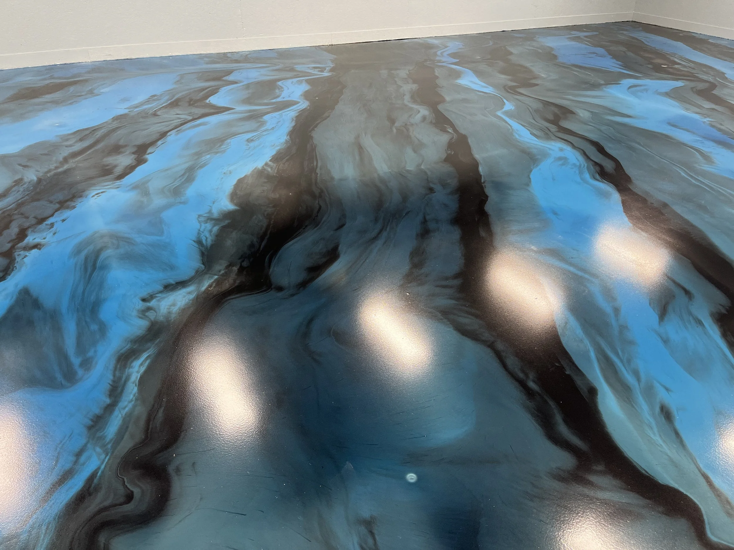 Abstract marbled flooring with swirling patterns of black, blue, and gray colors.