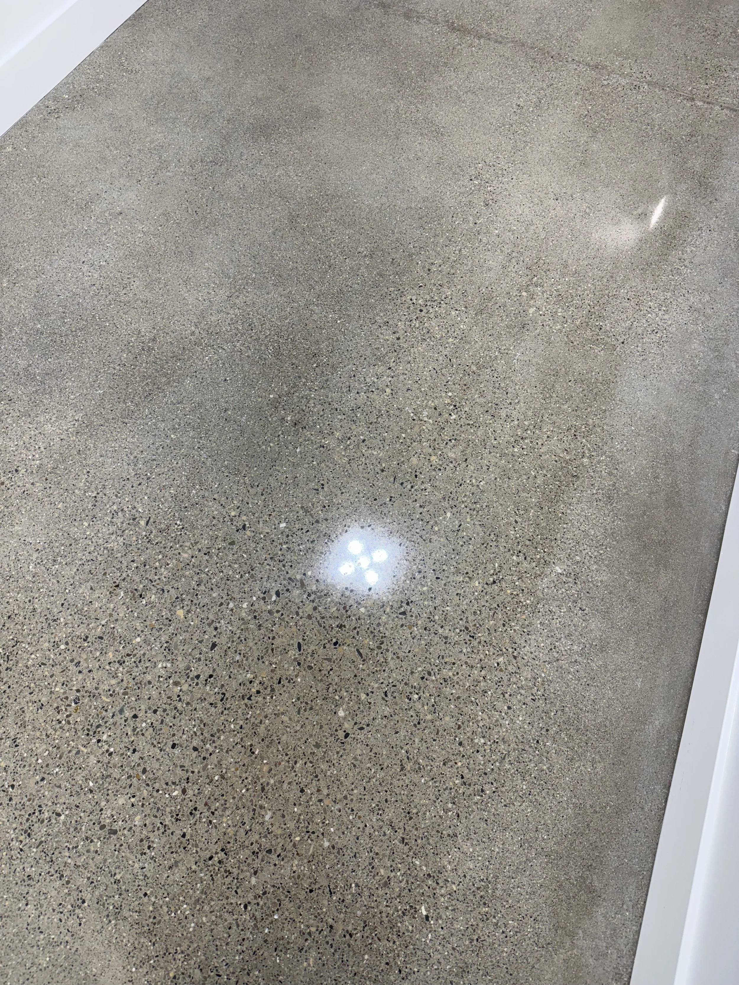 Polished concrete floor with a reflection of ceiling lights.