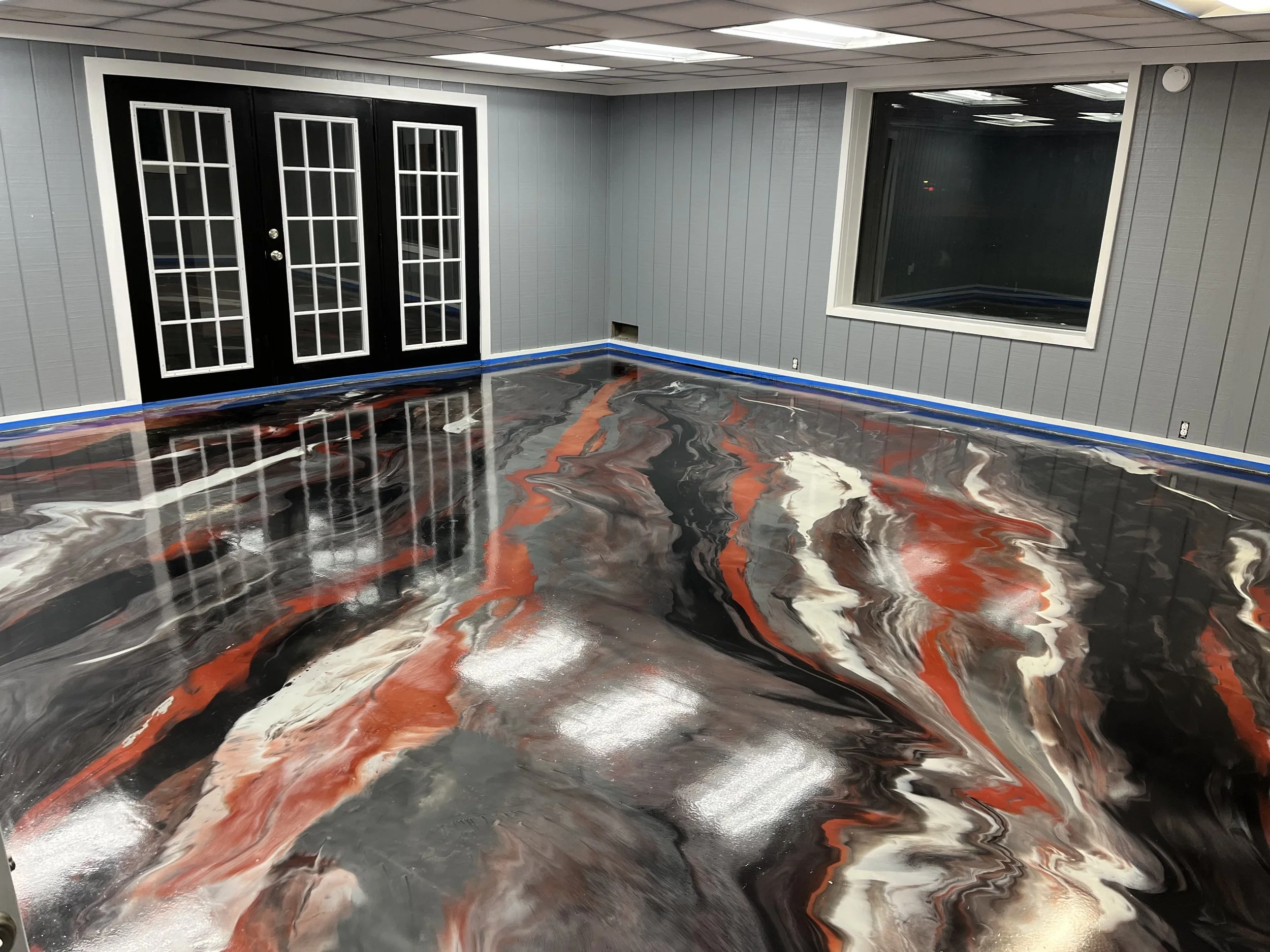 Interior room with gray paneled walls, a large window, a black double door with glass panes, and a highly reflective swirling marble-like floor in black, orange, white, and gray colors.