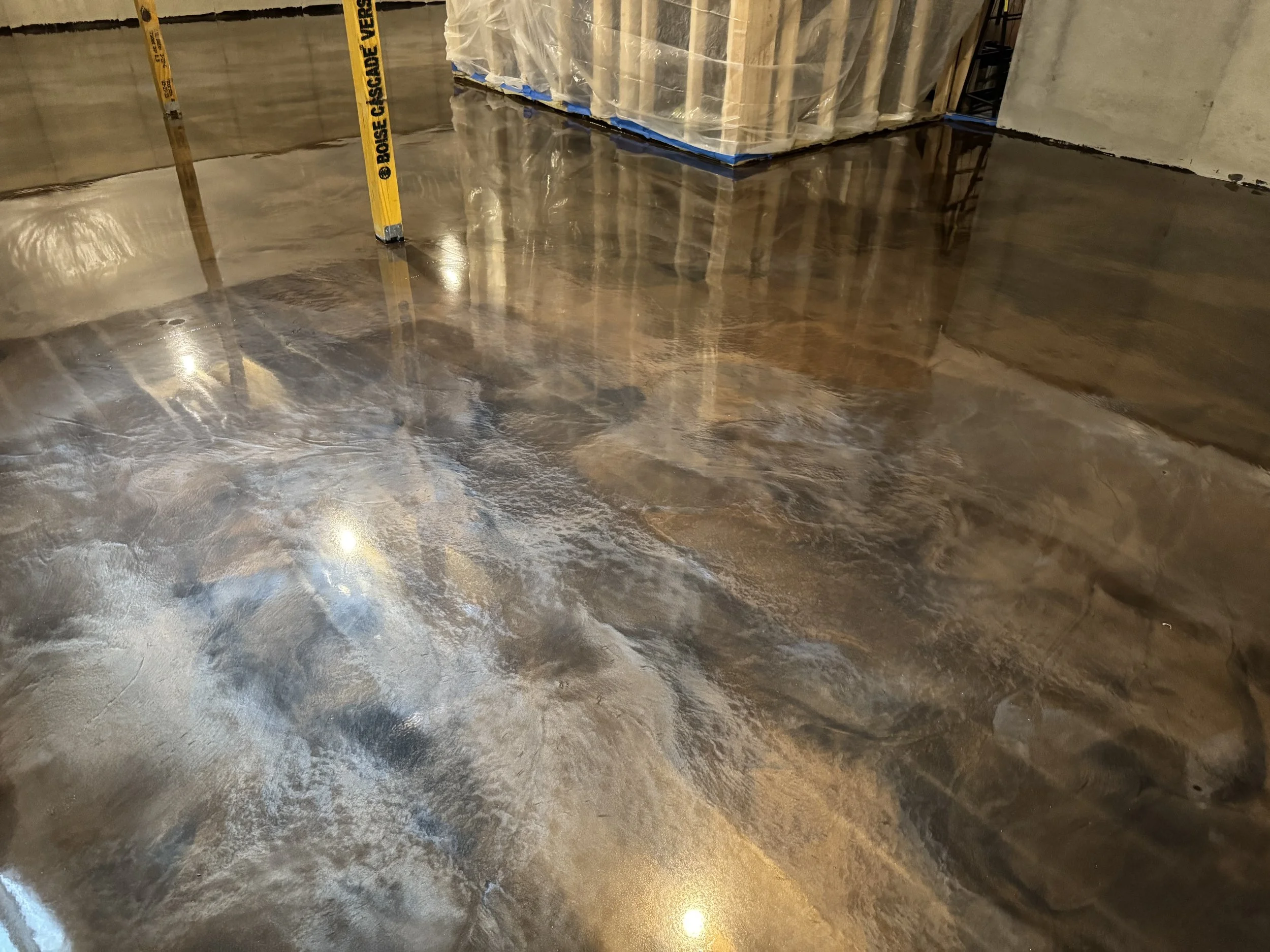 Polished concrete floor in an indoor construction site with ladders and building materials.