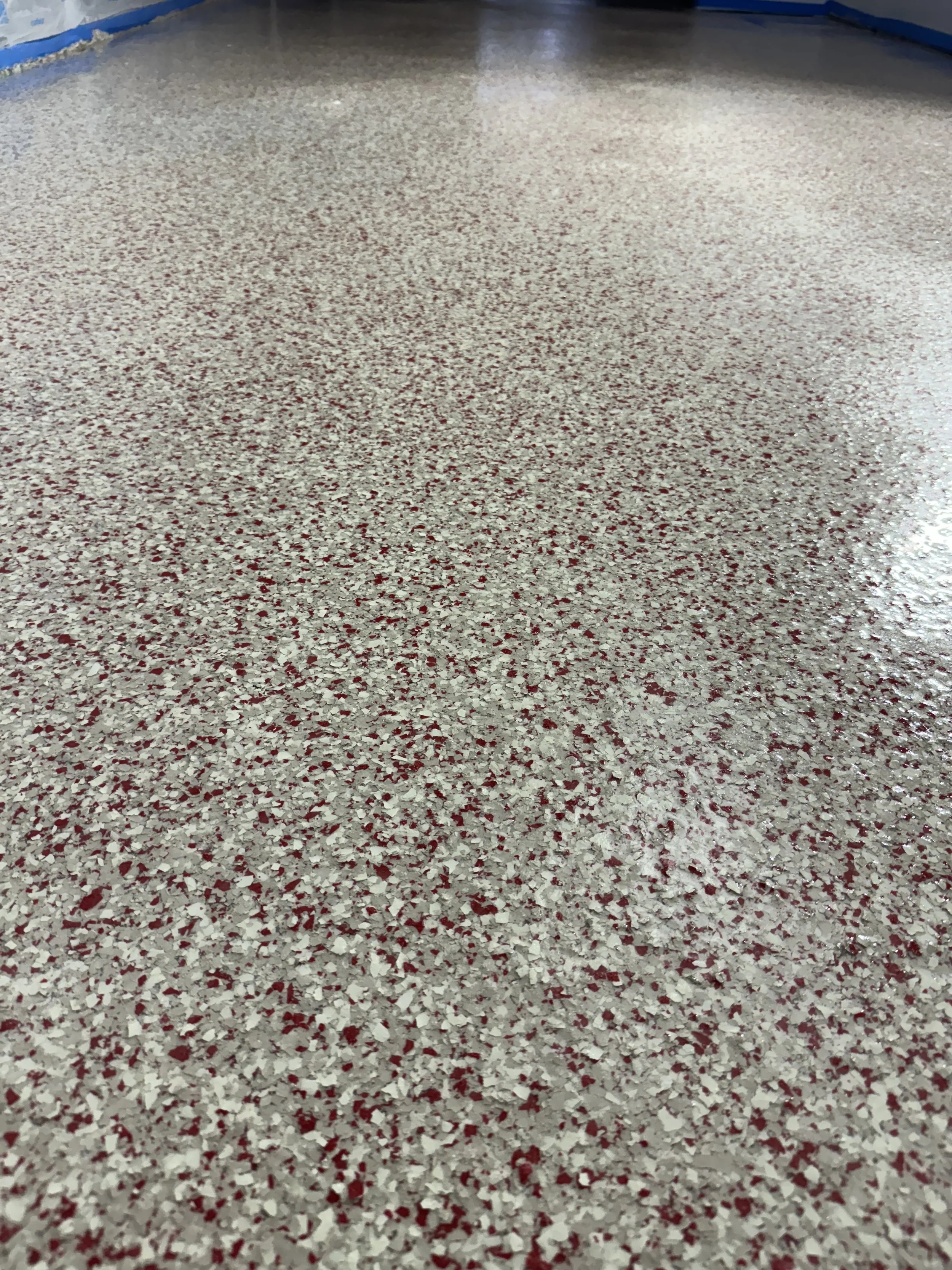 Close-up view of a speckled, polished indoor floor with a mix of beige and reddish-brown colors.