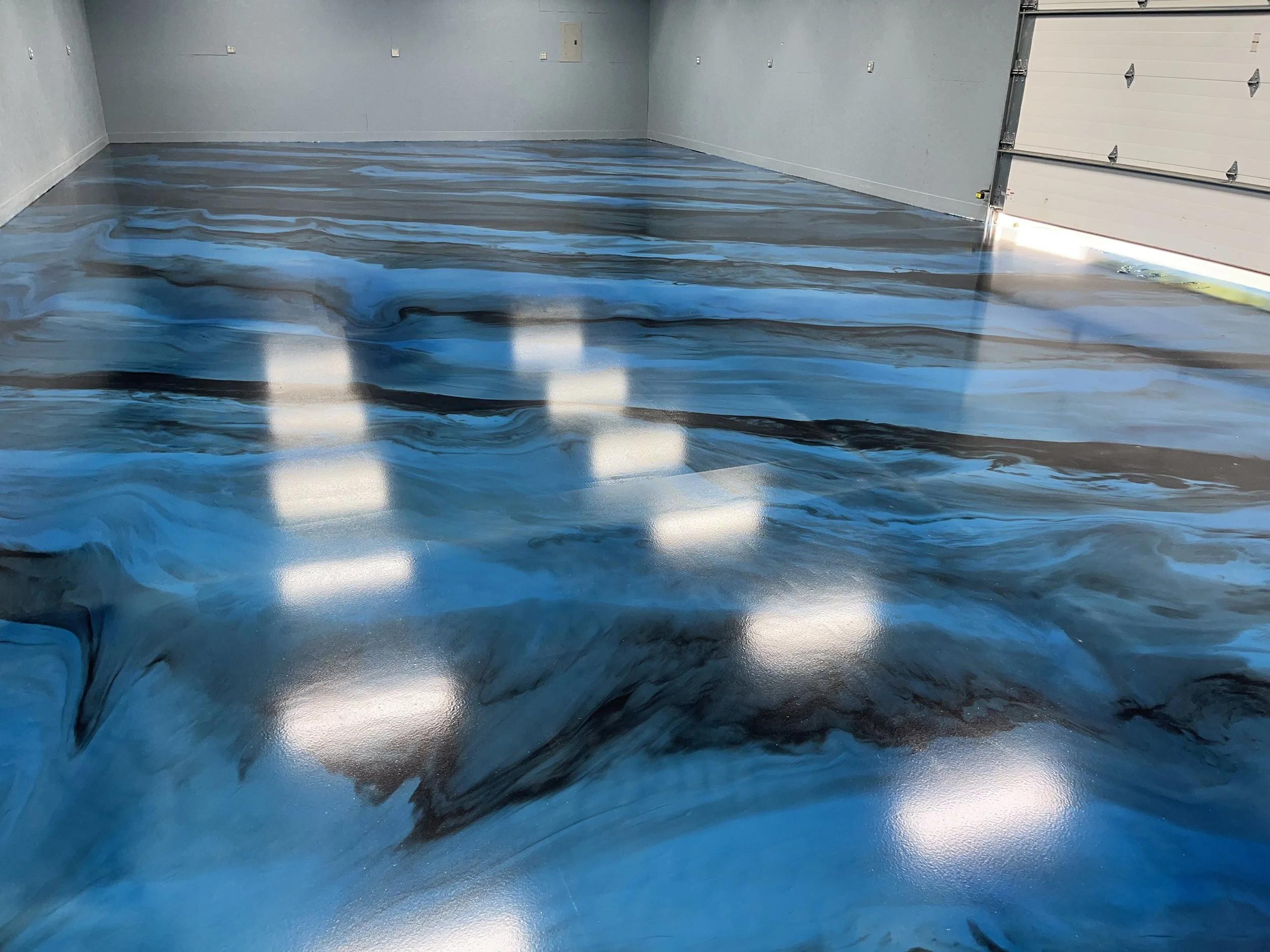 A garage floor with a custom epoxy coating that has a blue and black marbled pattern.
