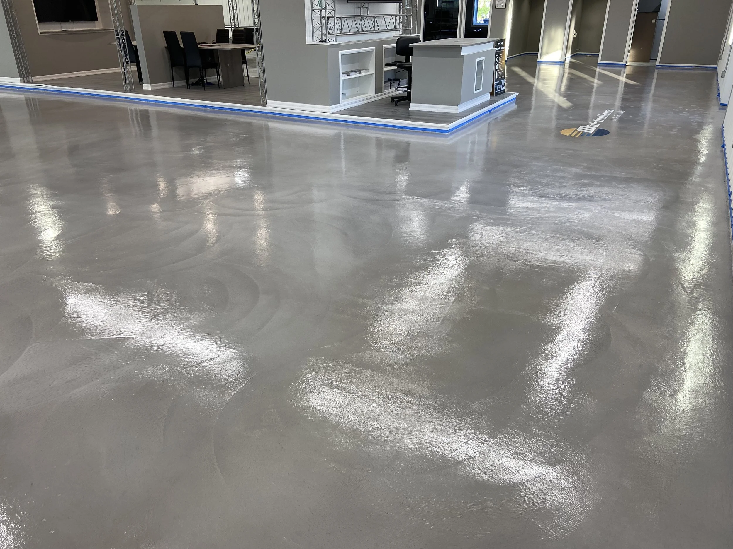 Interior view of a polished concrete floor in a modern commercial space with reception desk, office area, and open layout.