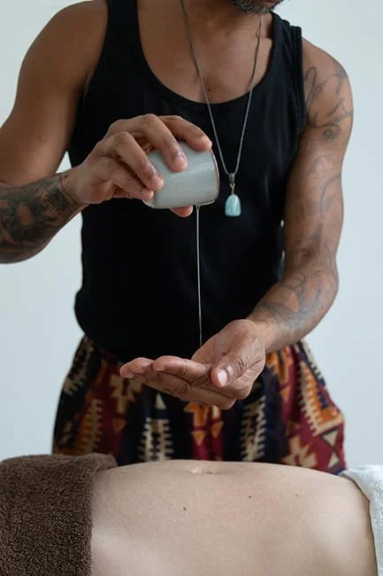 Une personne qui donne un massage ou une thérapie à une autre personne allongée, en utilisant un instrument ou une huile.