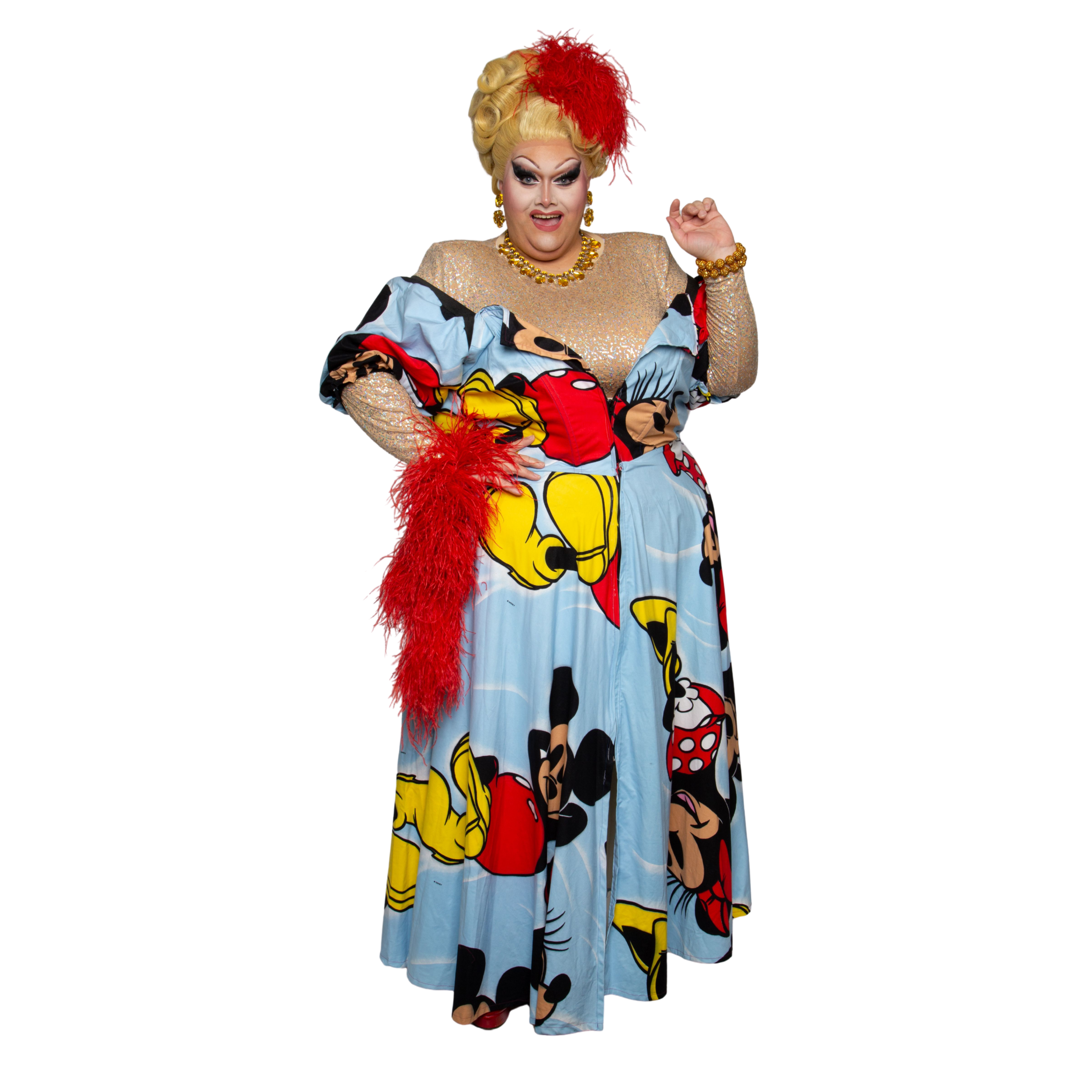 A drag queen dressed in a colorful Mickey Mouse themed gown, with a beige glittery top, red feathered accessories, bold makeup, and a large blonde wig adorned with a red feather.