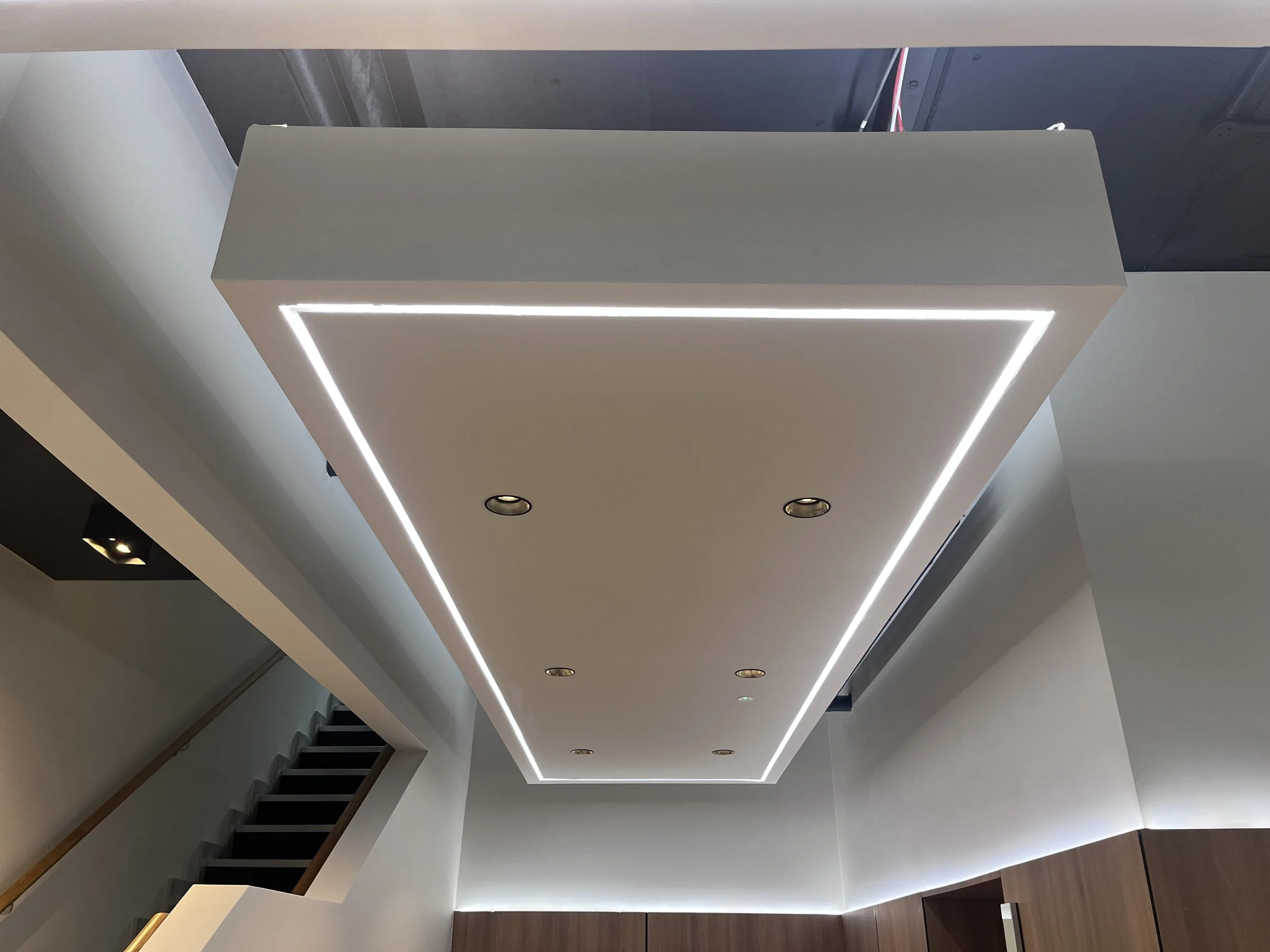 Modern ceiling with recessed lighting and LED strip lights in a contemporary interior space.