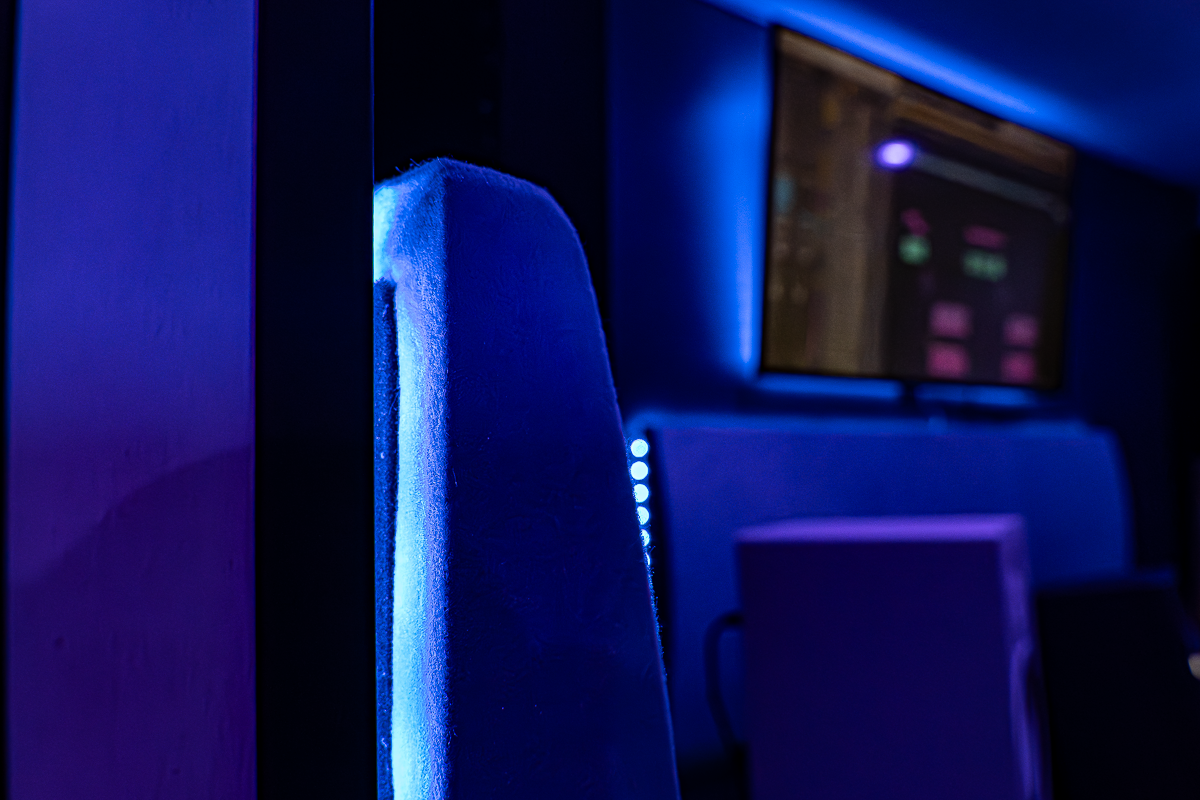 Studio d'enregistrement avec un siège et un écran lumineux en bleu et violet