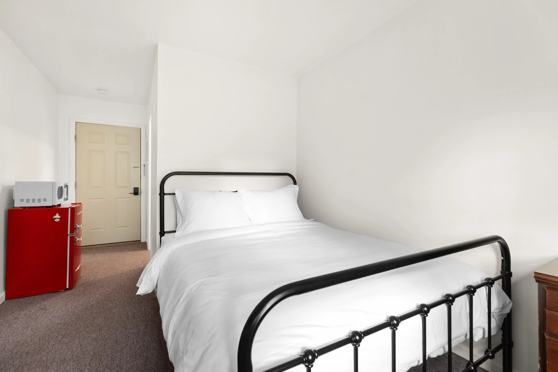 Single queen bed motel room near Cooperstown with clean white linens and desk