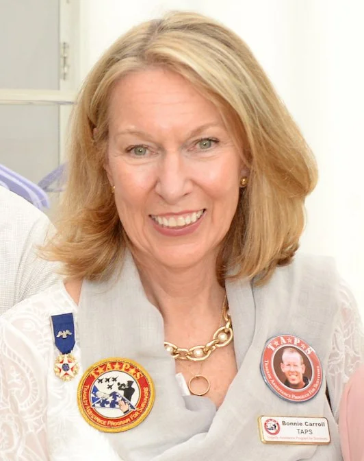 A headshot image of Bonnie Carroll in a white blouse and TAPS Buttons