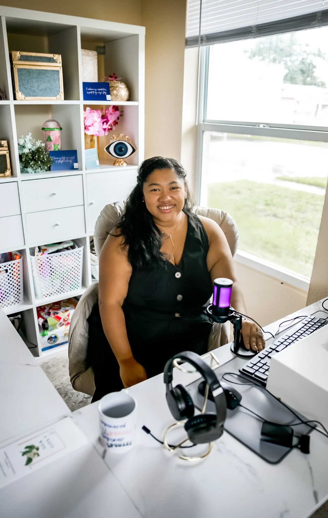 A photo of Reyna Worthy at her desk with podcasting equipment
