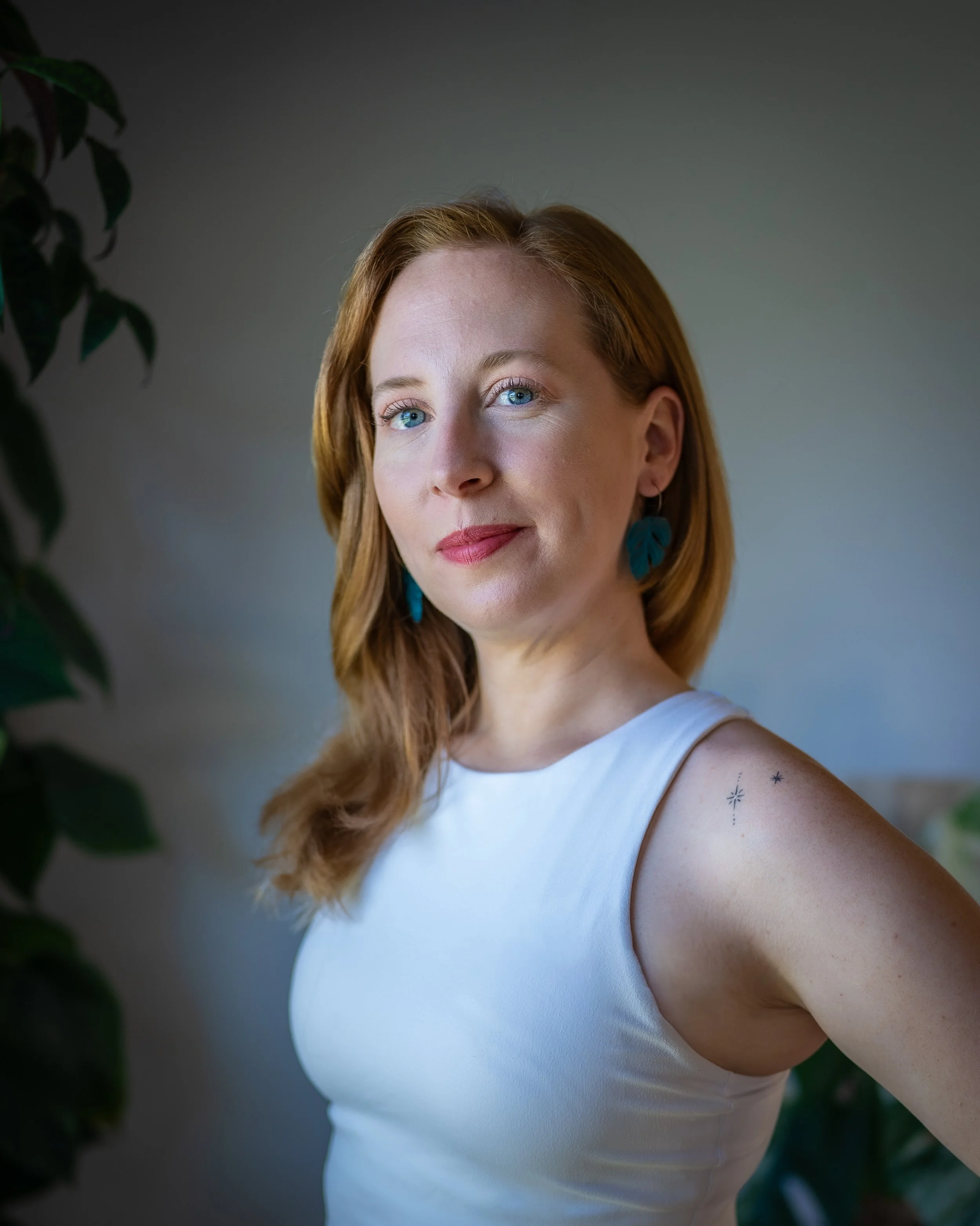 A photo of Britt Hall in a white tank and a bold lip.