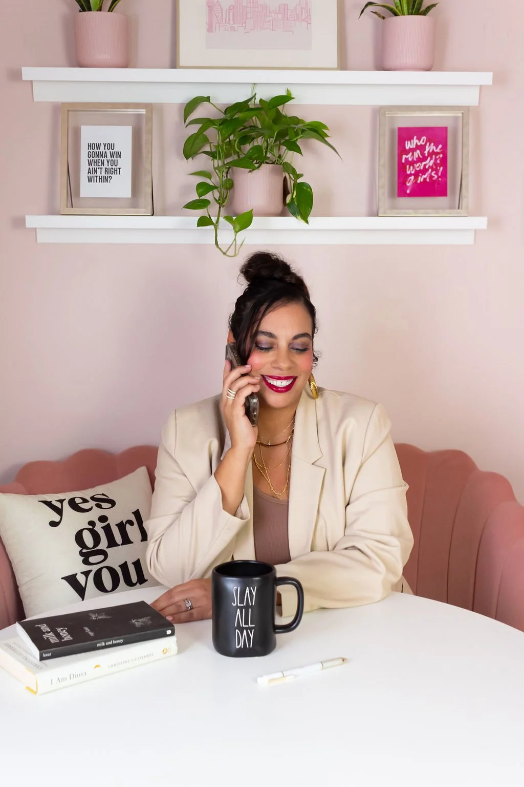 A photo of Monika Jefferson on the phone with a "Slay all day" mug.