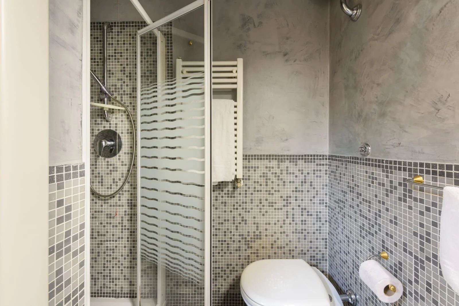 Another Image of a grey tiled toilet from a different angle, showing the shower and toilet