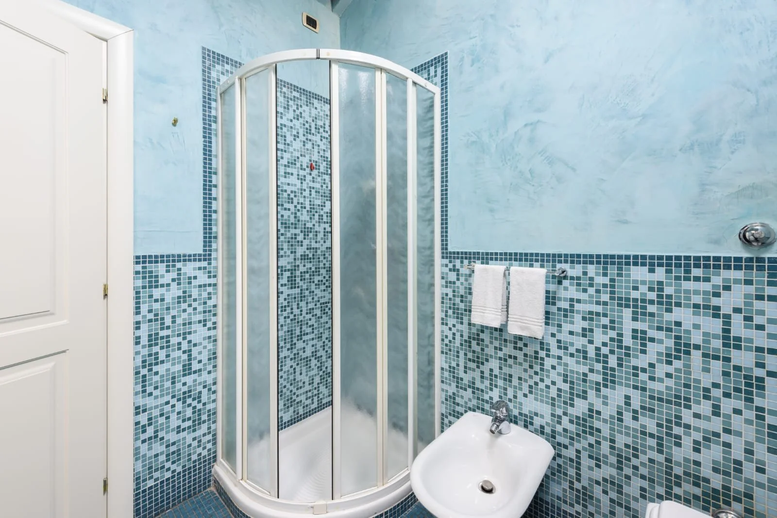 Image of a light blue tiled toilet with shower