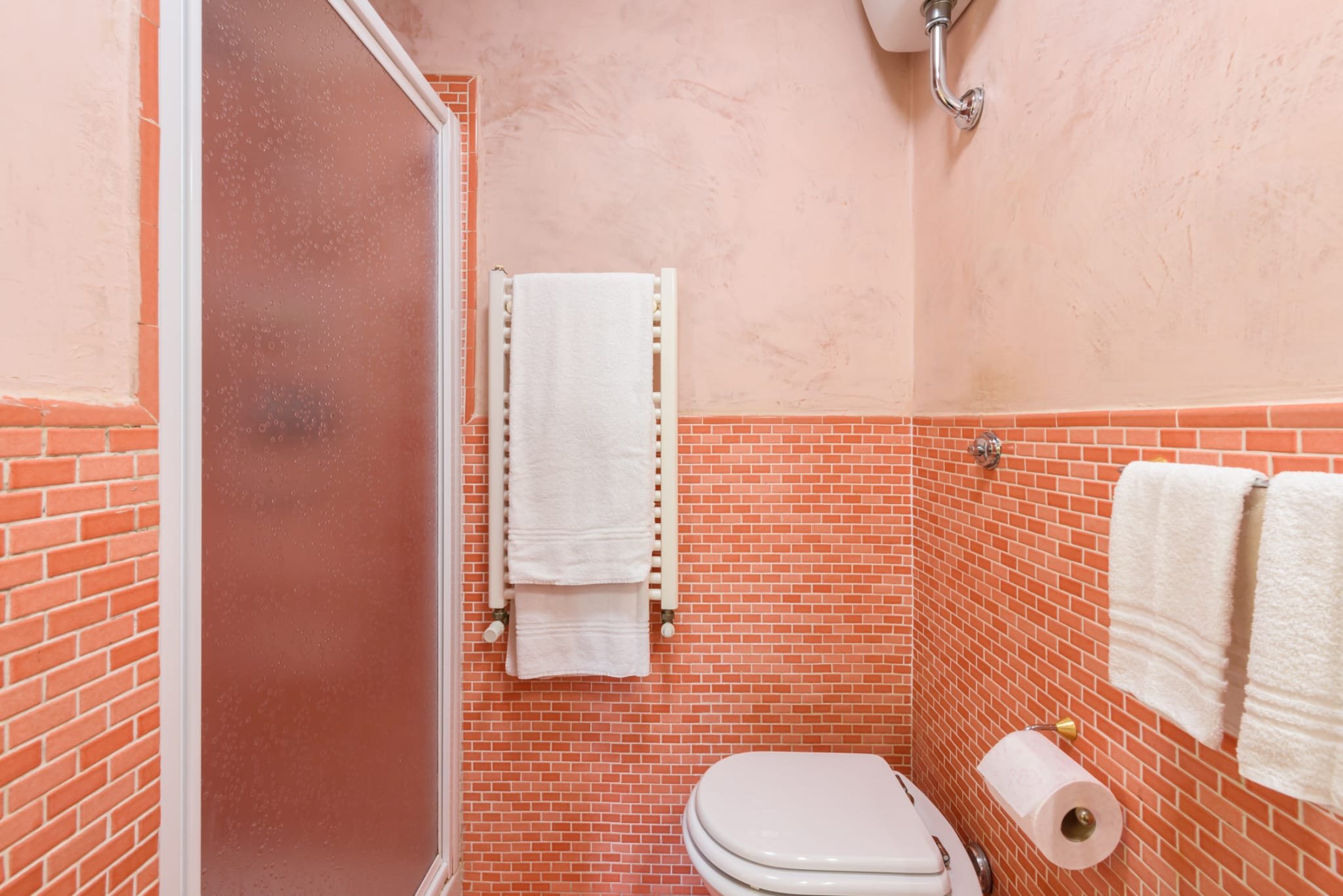 Image of a pinkish-red tiled toilet