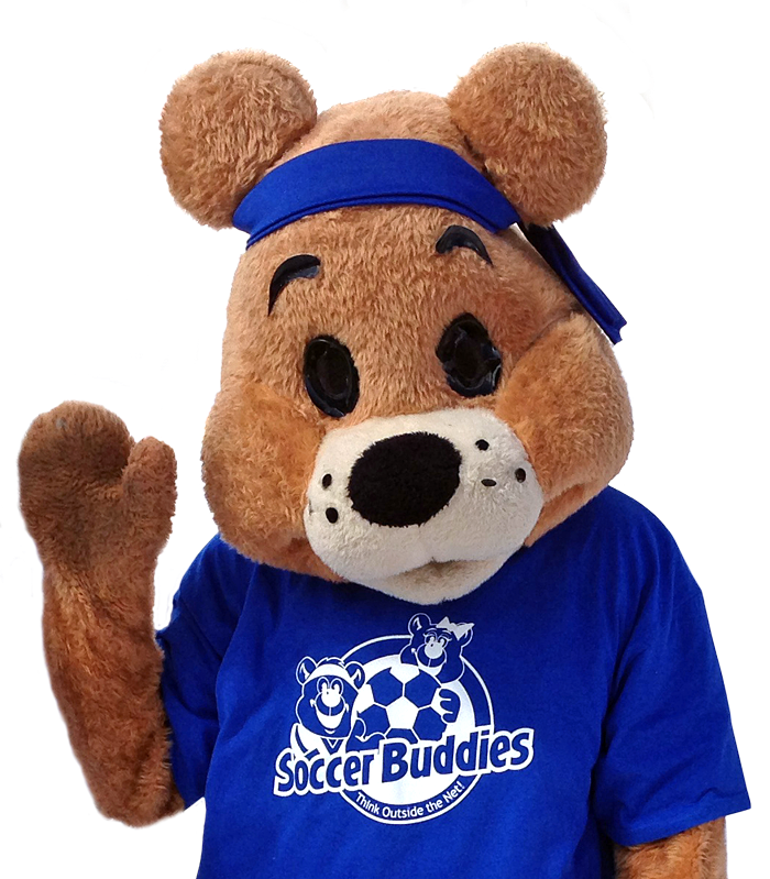 A person in a bear mascot costume wearing a blue T-shirt with soccer-themed cartoon characters and the text 'Soccer Buddies'. The mascot has a large black nose, black eyes, and a blue headband, and is waving with one paw.