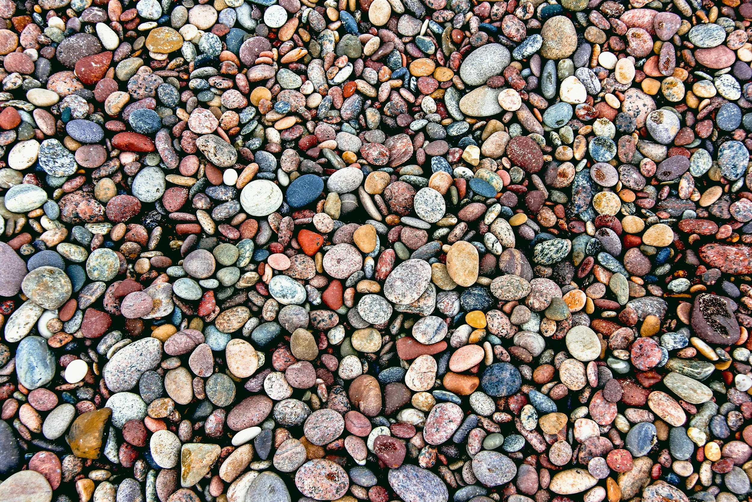 A close-up view of a large collection of small, multicolored pebbles on a beach.