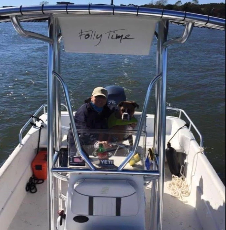 Person and dog on a boat with a handwritten sign that says "fallytime" hanging from the top of the boat's T-top.