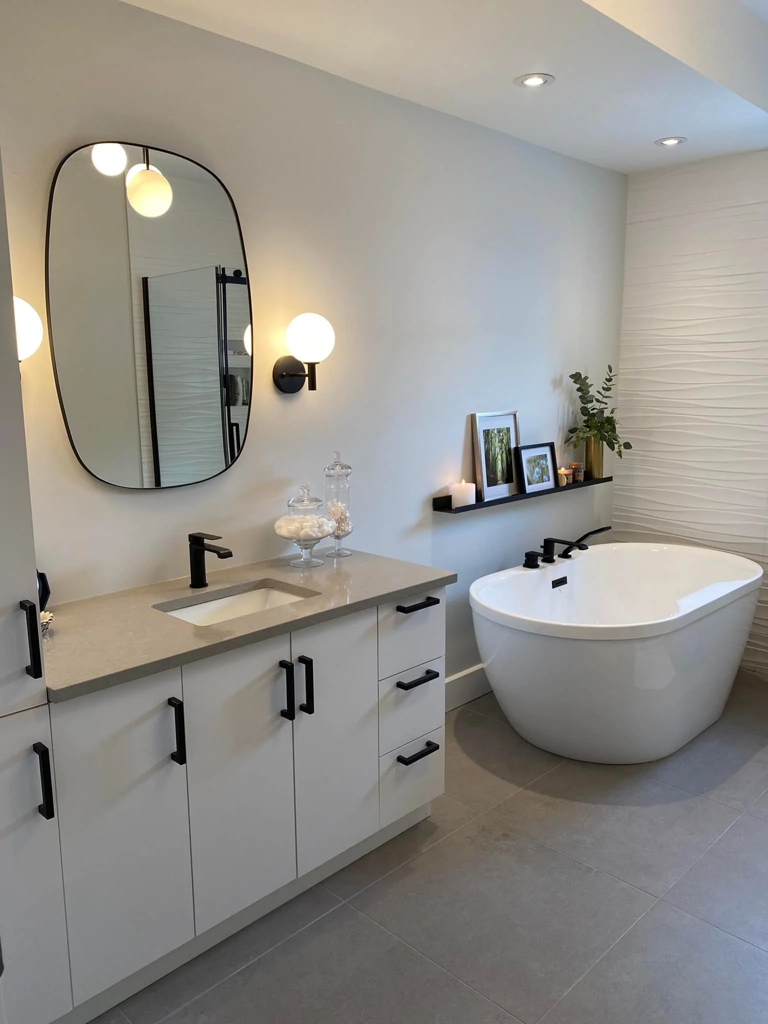 Salle de bain complètement rénovée munie d'un look moderne et épuré. Des lampes donnent une lumière tamisée et rajoutent une ambiance chaleureuse à la pièce. Projet réalisé par Chantal Rouiller, une designer d'intérieur d'expérience.