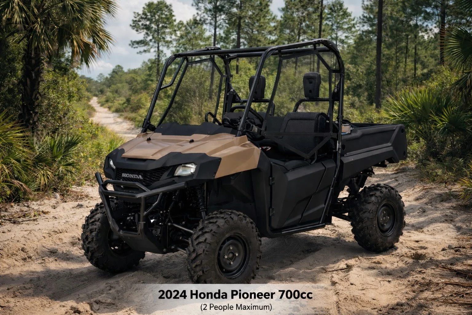 A 2024 Honda Pioneer 700cc utility terrain vehicle on a sandy trail in a forested area with lush green trees and bushes, designed for a maximum of two people.