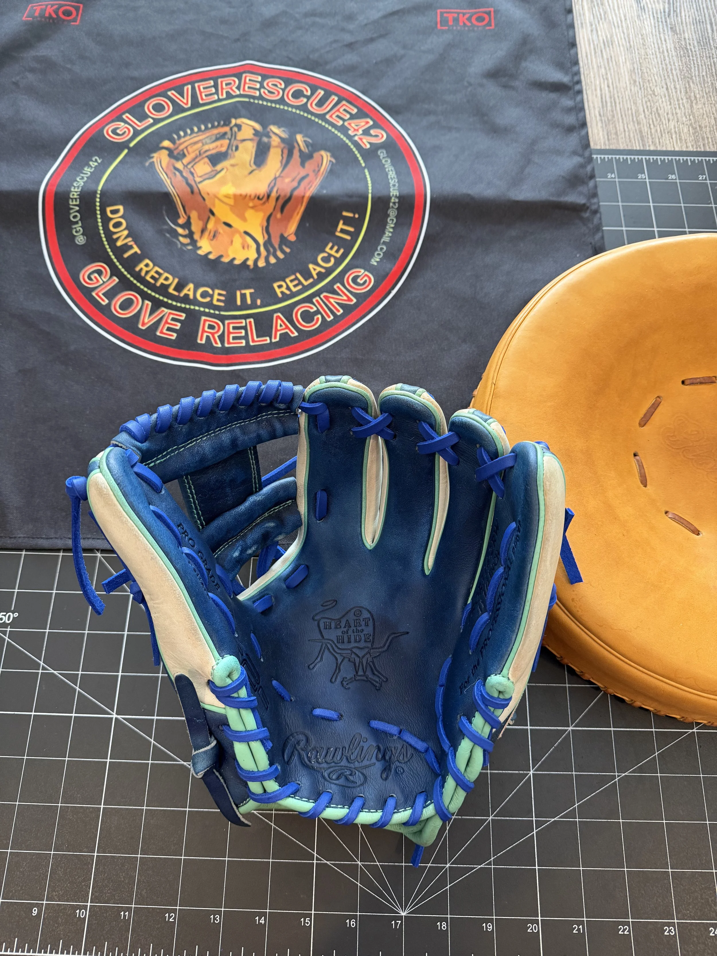 A baseball glove, a leather catcher's mask, and a cloth with a circular logo that says 'GLOVERESCUE42' and 'Don't replace it, relace it! Love relacing.'