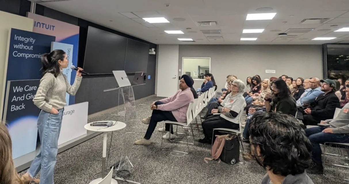 Pansy is giving a presentation using a microphone in a conference room with an audience seated and listening.