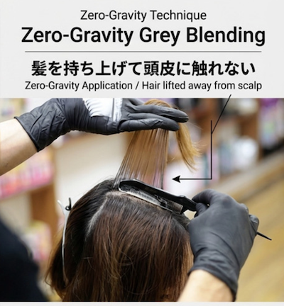 A person wearing black gloves applying Grey Blending hair color technique to a woman's hair, with the instruction to lift hair away from the scalp.