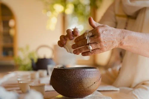 Person washing hands over a ceramic bowl in a cozy indoor setting
